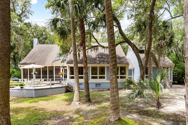 2653 Seabrook Island Rd, Seabrook Island, SC 29455 - back of property with a sunroom, a shingled roof, a chimney, a wooden deck, and a lawn