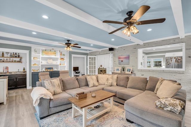 living room featuring bar, beam ceiling, ceiling fan, and light wood-type flooring