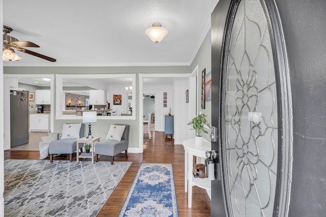 foyer featuring crown molding, ceiling fan with notable chandelier, and dark hardwood / wood-style flooring