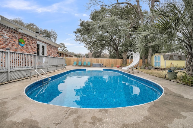 view of pool with a water slide, a patio area, and a shed