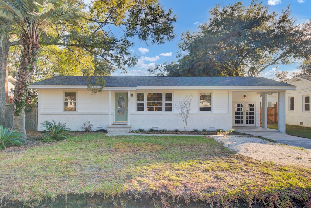 single story home with french doors and a front lawn