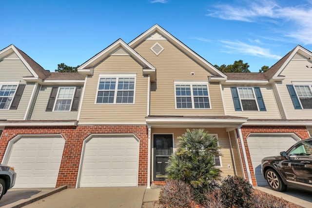 view of property with driveway, an attached garage, and brick siding