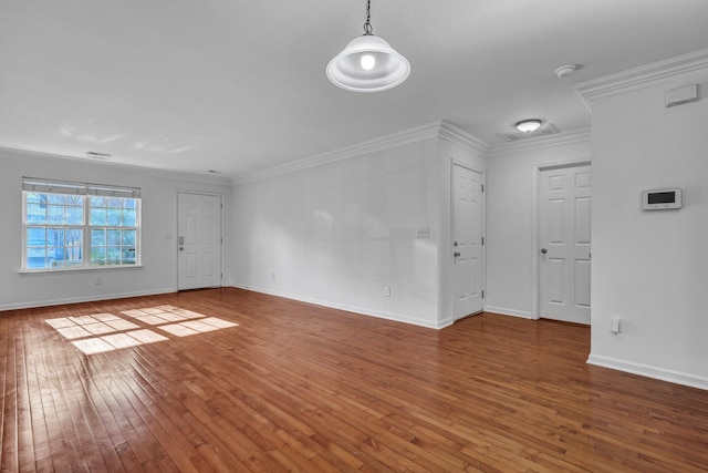 unfurnished living room with baseboards, hardwood / wood-style floors, visible vents, and crown molding