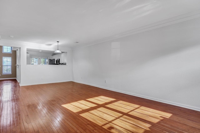 unfurnished living room with baseboards, wood-type flooring, and crown molding