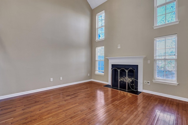 unfurnished living room featuring a healthy amount of sunlight, wood-type flooring, a fireplace, and baseboards