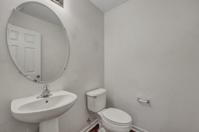 bathroom featuring baseboards, a sink, and toilet