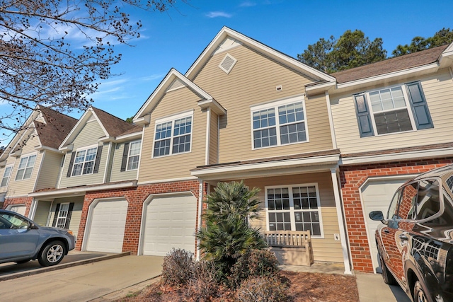 view of property with covered porch, brick siding, driveway, and an attached garage