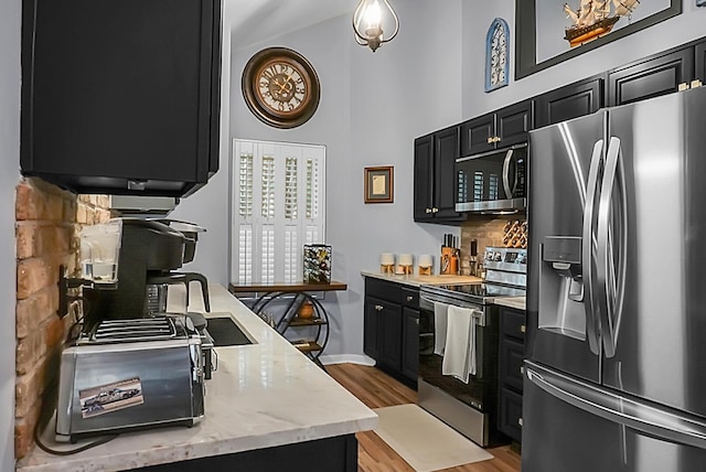 7886 Racquet Rd, North Charleston, SC 29418 - kitchen with stainless steel appliances, dark cabinetry, decorative backsplash, high vaulted ceiling, and light wood-type flooring