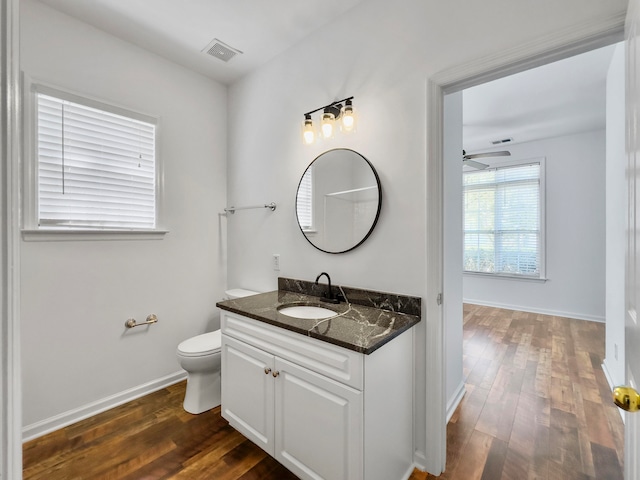 bathroom featuring vanity, toilet, hardwood / wood-style flooring, and ceiling fan