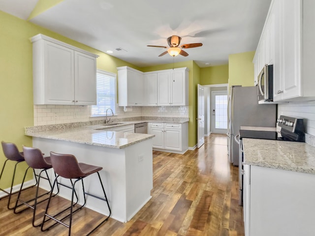 kitchen with white cabinetry, kitchen peninsula, light hardwood / wood-style floors, stove, and sink