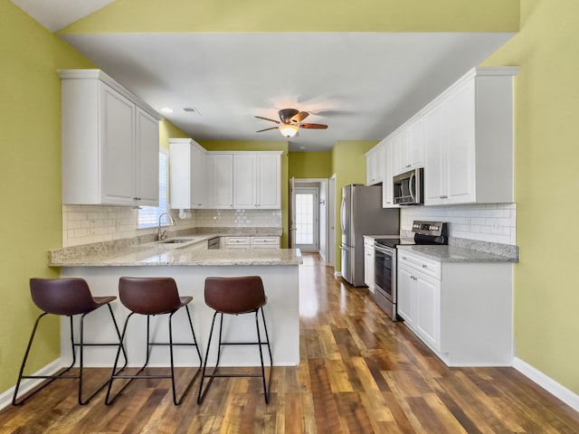 kitchen with appliances with stainless steel finishes, dark hardwood / wood-style flooring, white cabinets, and plenty of natural light