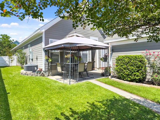 rear view of property featuring central air condition unit, a gazebo, a patio area, and a lawn