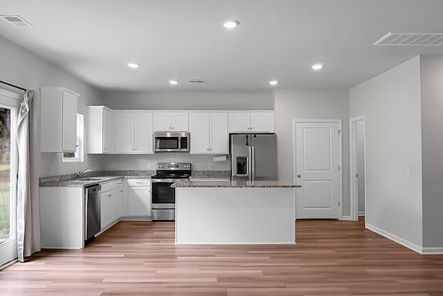717 Butter Rd, Bonneau, SC 29431 - kitchen featuring stainless steel appliances, a center island, light wood-style floors, white cabinets, and stone counters
