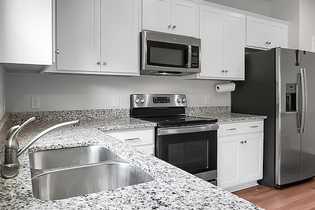 717 Butter Rd, Bonneau, SC 29431 - kitchen with appliances with stainless steel finishes, white cabinets, light stone countertops, and wood finished floors