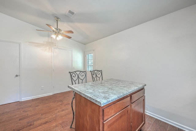 interior space featuring vaulted ceiling, a kitchen island, ceiling fan, and dark wood-type flooring