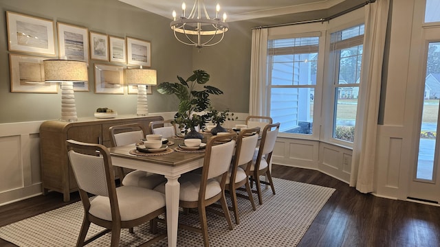 dining space with an inviting chandelier, a decorative wall, and dark wood-type flooring