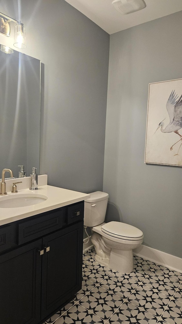 half bathroom featuring baseboards, toilet, and vanity