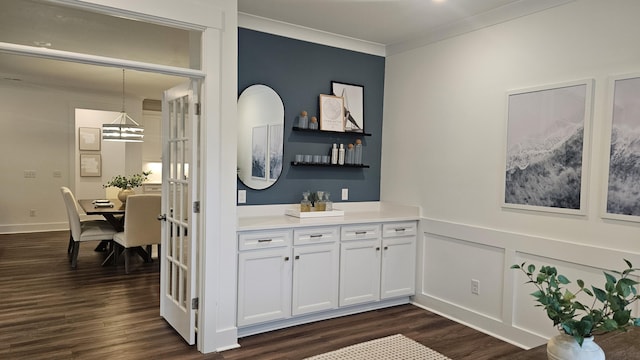 bar featuring decorative light fixtures, crown molding, a bar, and dark wood-type flooring