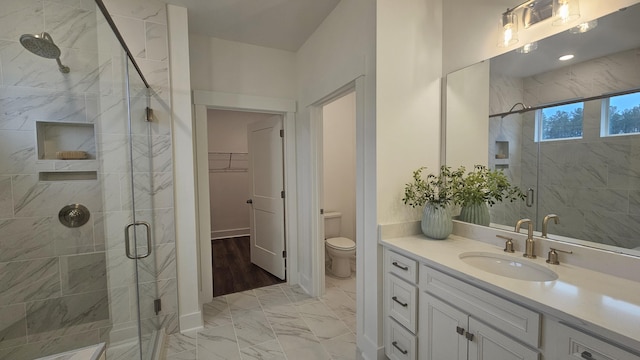 bathroom with marble finish floor, a stall shower, vanity, and a walk in closet