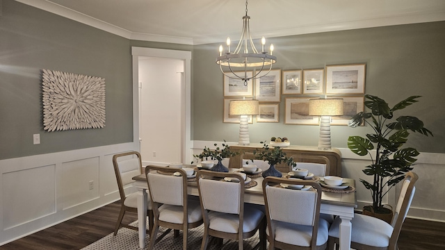 dining space with dark wood-type flooring, ornamental molding, wainscoting, a decorative wall, and a chandelier