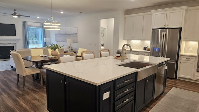 kitchen with open floor plan, stainless steel appliances, white cabinetry, a ceiling fan, and dark cabinets