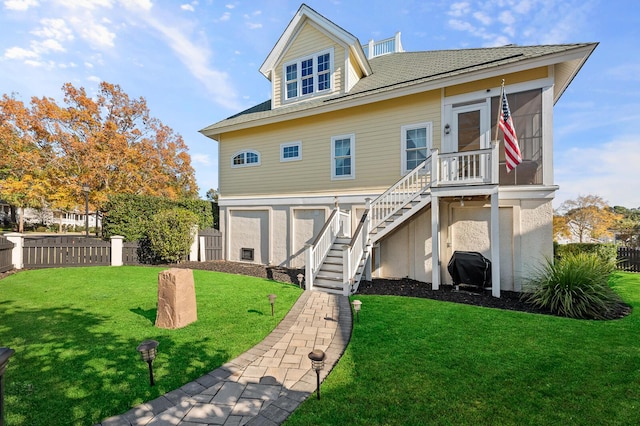 coastal home with stairs, a front lawn, fence, and stucco siding