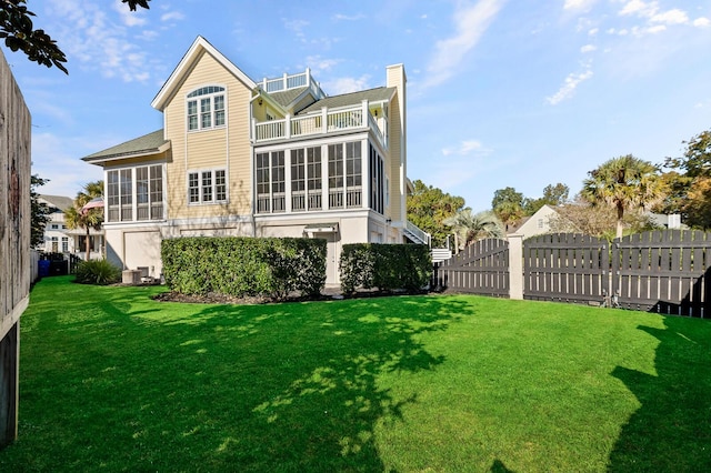 rear view of property featuring a yard, a sunroom, fence, and a chimney