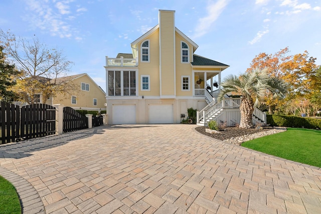 view of front of property with decorative driveway, a chimney, covered porch, stairway, and an attached garage