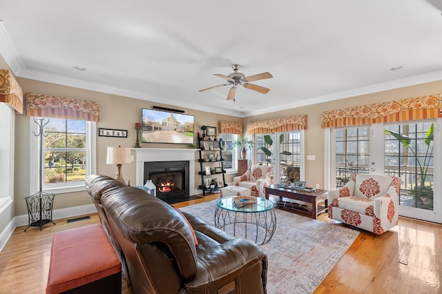 living area with light wood-style floors, a fireplace with flush hearth, visible vents, and crown molding