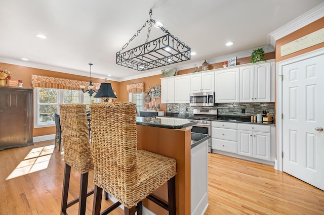 kitchen with appliances with stainless steel finishes, dark countertops, white cabinets, and a kitchen breakfast bar