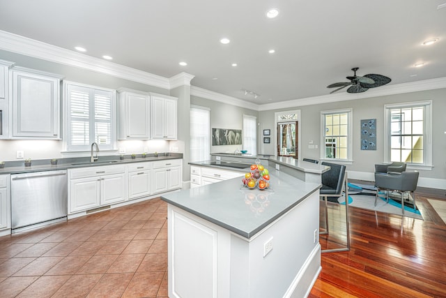 kitchen with a sink, crown molding, white cabinets, and stainless steel dishwasher