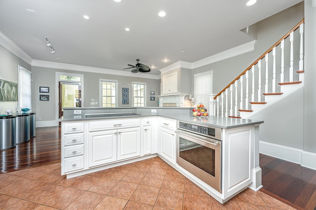 kitchen featuring light tile patterned floors, oven, ornamental molding, and black electric cooktop