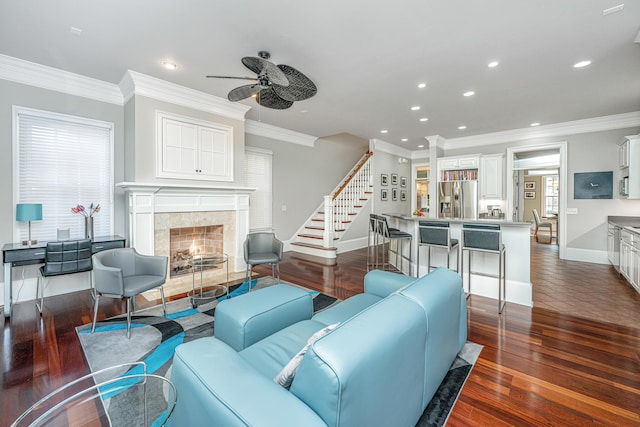 living room featuring recessed lighting, dark wood-type flooring, a fireplace, baseboards, and ornamental molding