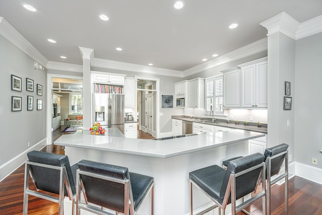 kitchen with stainless steel appliances, plenty of natural light, dark wood finished floors, and a sink