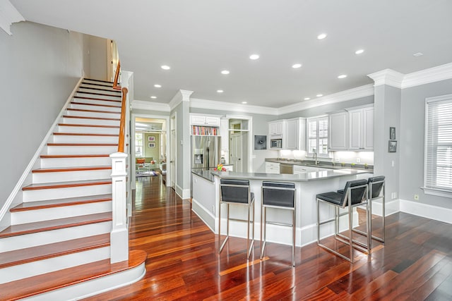 kitchen with a breakfast bar area, a spacious island, baseboards, appliances with stainless steel finishes, and dark wood-style floors