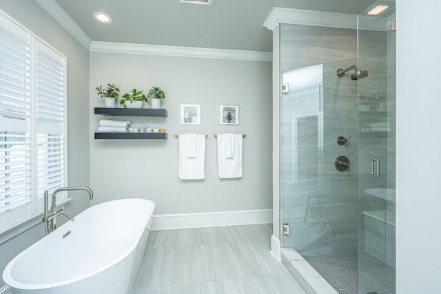 bathroom featuring a shower stall, ornamental molding, a freestanding tub, and baseboards