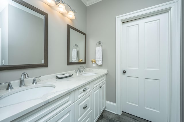 full bath featuring double vanity, wood finished floors, a sink, and baseboards