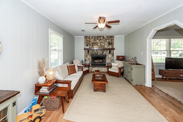 living area with crown molding, ceiling fan, a fireplace, and wood finished floors