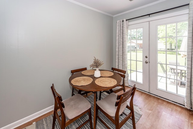 dining space featuring baseboards, ornamental molding, french doors, and light wood finished floors