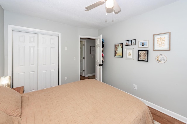 bedroom with a ceiling fan, baseboards, wood finished floors, and a closet
