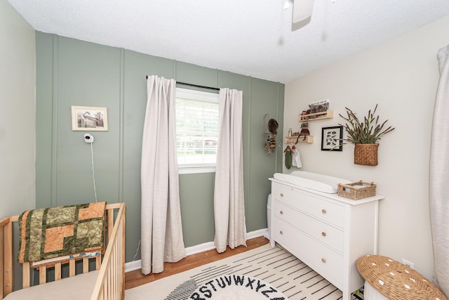 bedroom featuring baseboards, light wood finished floors, and ceiling fan