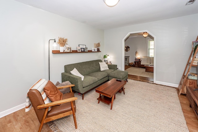 living room with baseboards, arched walkways, and wood finished floors