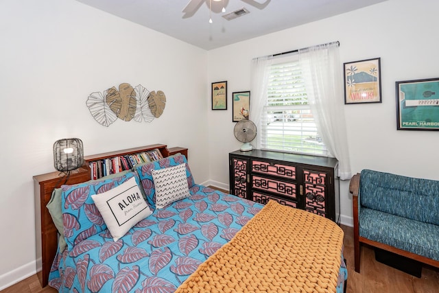 bedroom featuring baseboards, a ceiling fan, wood finished floors, and visible vents