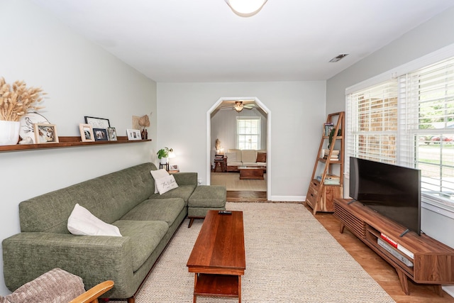 living area with arched walkways, baseboards, wood finished floors, and visible vents