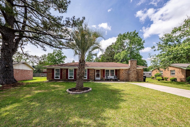 single story home featuring brick siding, driveway, a chimney, and a front lawn