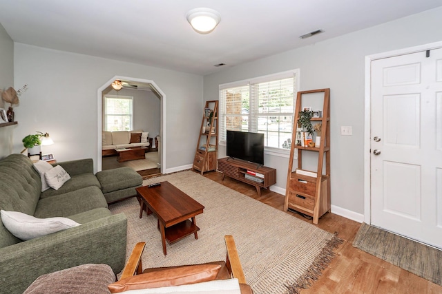 living room with visible vents, arched walkways, baseboards, and wood finished floors
