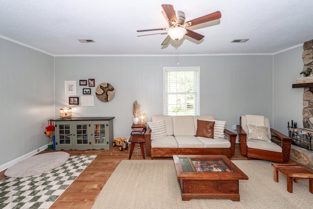 living area with ceiling fan, visible vents, ornamental molding, and wood finished floors