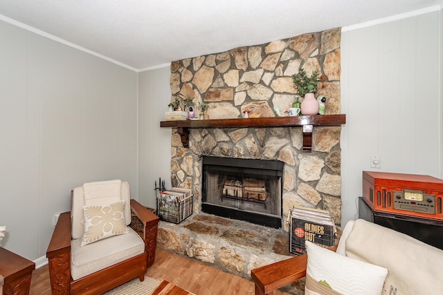 living area featuring crown molding, a stone fireplace, and wood finished floors