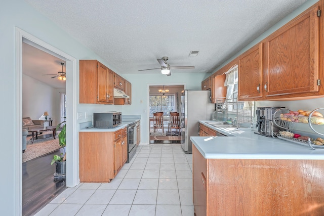 kitchen with ceiling fan with notable chandelier, sink, light tile patterned floors, stainless steel appliances, and a textured ceiling