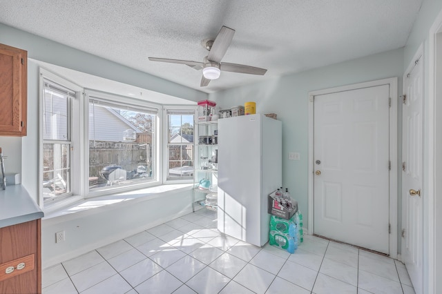 entryway featuring light tile patterned floors, a textured ceiling, and ceiling fan